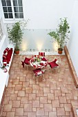 Tiled courtyard with masonry bench and romantically decorated seating area with red cushions