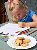 A little girl with a school book and cookies