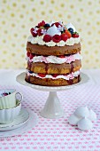An Eton Mess layer cake with strawberries, raspberries and blueberries on a cake stand