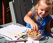A little girl snacking on nuts while doing her homework