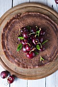Chocolate crepes with cherries on a wooden plate (seen from above)