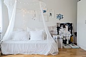 Canopy and fairy lights above romantic daybed with vintage pillows