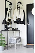 Delicate console table and coat rack in black and white foyer