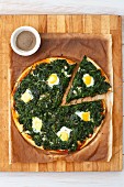 Pizza fiorentina with spinach and quail eggs, sliced