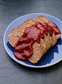 Meat loaf with tomato sauce on a blue plate