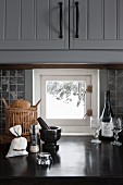 Detail of utensils and bread basket on kitchen counter in front of small window