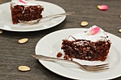 Two slices of chocolate almond cake on plates (Italy)