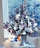 Small Christmas tree lavishly decorated with baubles & artificial snow