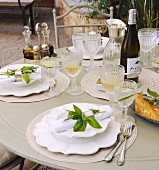 A festively laid garden table with bunches on herbs as napkin decorations