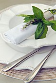 A white place setting decorated with a bouquet of herbs