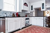 Traditionell gemusterter, rotweisser Teppich in moderner Landhausküche, roter Blumentopf mit Weihnachtsstern
