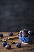 Fresh plums in a ceramic bowl and next to it