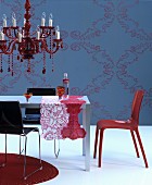 Red chandelier above table with patterned runners in front of blue wall with ornate pattern