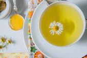 A cup of chamomile tea with a chamomile flower (seen from above)