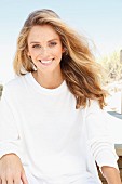 A young woman on a beach wearing a long-sleeved white top