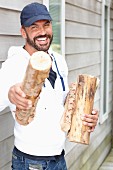 A casually dressed man with logs