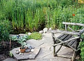 Stone-flagged seating area in garden next to small pond and bog garden