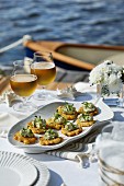 A table by the water laid with corn fritters and beer