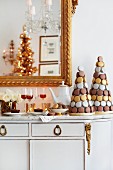 Macaron-Bäumchen mit Kaffeekanne und Dessertweingläsern auf weisser Esszimmerkommode mit Goldverzierungen