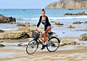 Blonde Frau fährt Fahrrad am Strand