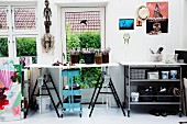 Work table on trestles above turquoise-painted trolley with shelves in front of terrace door