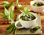 Wild herb pesto in a cup on a wooden board
