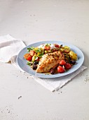 Chicken breast baked on a tray with a potato and tomato salad with pesto