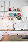 Blick über Arbeitsplatte aus Beton auf weiss gefliester Wand mit String-Regal über Küchenzeile