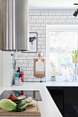 L-shaped kitchen counter with integrated induction hob below cylindrical extractor hood