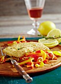 Fried cod fillets with a polenta coating on a pepper medley