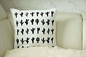 White cushion with printed pattern of black cacti