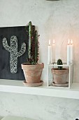 Potted cacti, candlesticks and hand-made string art on black background