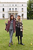 Two women wearing checked outfits playing croquet