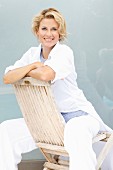 A blonde woman sitting backwards on a wooden chair