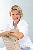 A blonde woman sitting backwards on a wooden chair