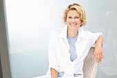 A blonde woman sitting on a wooden chair