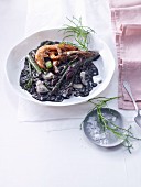 Black risotto with prawns, green asparagus and santolina