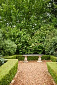 Steinbank in antik griechischem Stil in gestaltetem Garten mit Hecken