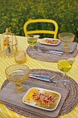 Orangendessert für Zwei auf gelb-weiß gestreifter Tischdecke und rustikalen Tischsets