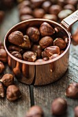 Hazelnuts in a copper cup and on a wooden surface