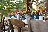 Gedeckter, rustikaler Holztisch mit mit Herbstblumen dekoriert, im Freien