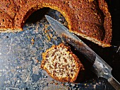 Sliced rum and nut cake with a knife on a baking tray