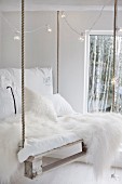 White sheepskin, white cushions and fairy lights on DIY pallet swing