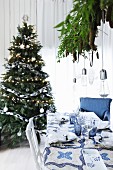Gedeckter Weihnachtstisch in Blau-Weiß vor einem Weihnachtsbaum