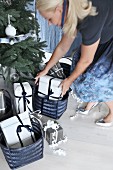 Woman bending down to place presents below Christmas tree