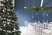 Christmas dining table set in blue and white next to decorated Christmas tree