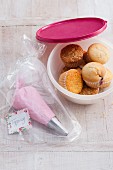 A piping bag filled with a topping in a freezer bag with muffins in a Tupperware box