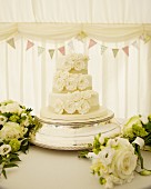 White wedding cake surrounded by bouquets