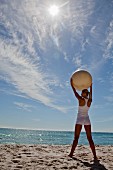 A woman on a beach doing yoga stretching with an exercise ball