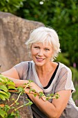 A blonde woman leaning on a rock